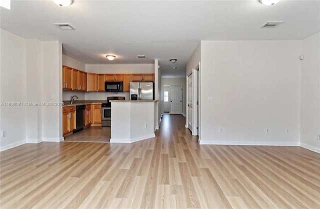 2872 SW 127th Way Unit 1, Miramar, FL 33027 - kitchen with appliances with stainless steel finishes, open floor plan, light wood-type flooring, and brown cabinets