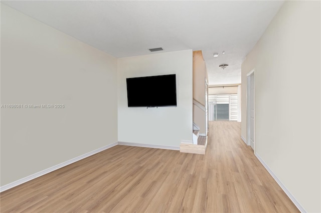 unfurnished living room with light wood-style floors, visible vents, baseboards, and stairs