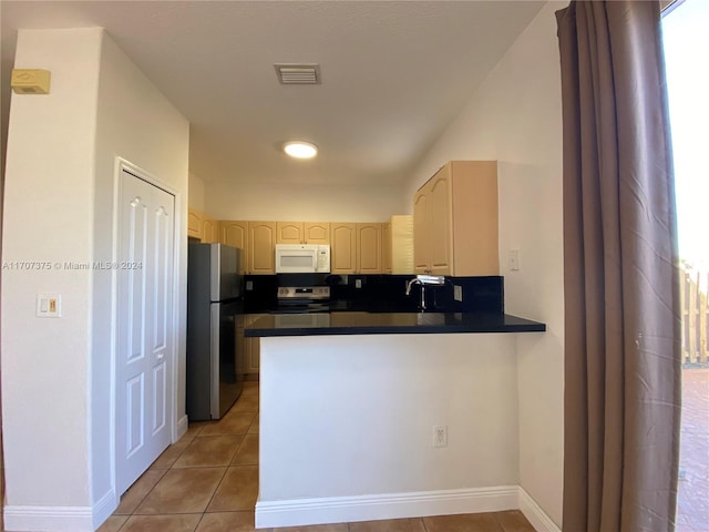 kitchen featuring tile patterned floors, kitchen peninsula, stainless steel appliances, and light brown cabinetry