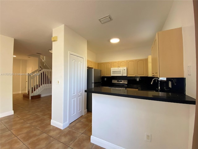 kitchen with sink, tile patterned flooring, tasteful backsplash, kitchen peninsula, and stainless steel appliances