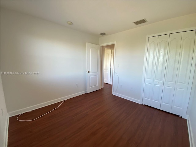 unfurnished bedroom with dark hardwood / wood-style floors and a closet