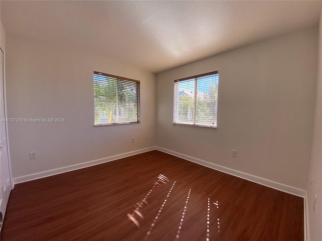 spare room with a textured ceiling and dark hardwood / wood-style flooring