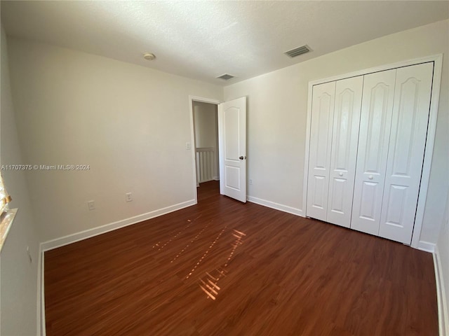 unfurnished bedroom featuring a closet, dark wood-type flooring, and a textured ceiling