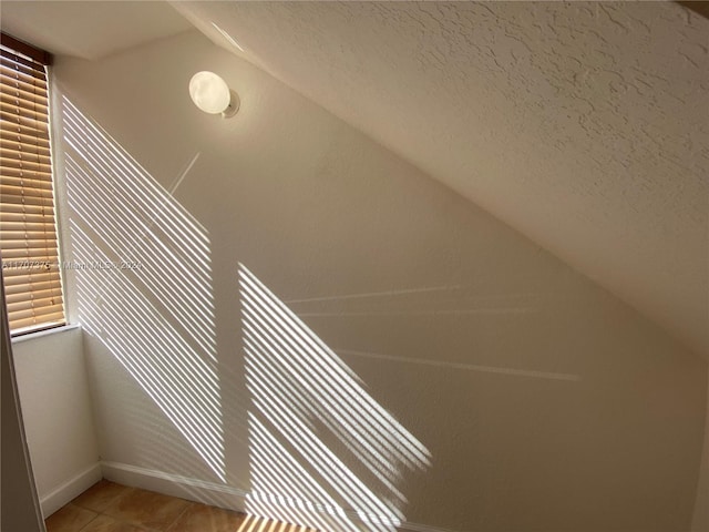 bonus room featuring a textured ceiling, tile patterned floors, and lofted ceiling