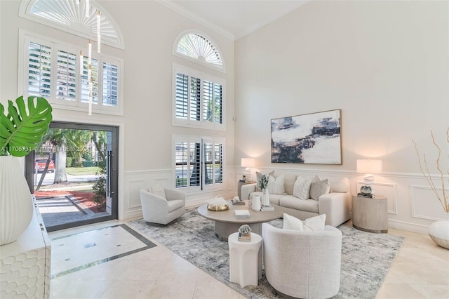 living room featuring tile patterned flooring, a high ceiling, plenty of natural light, and ornamental molding