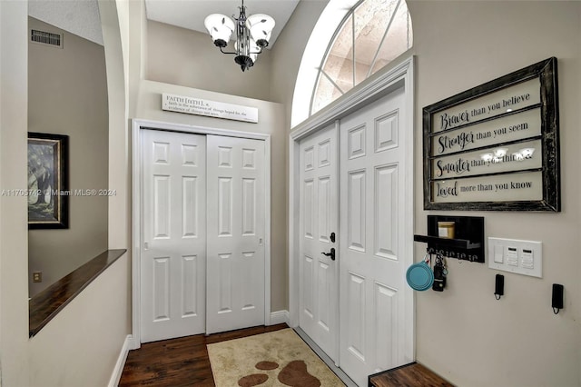 entryway with dark hardwood / wood-style flooring, lofted ceiling, and an inviting chandelier