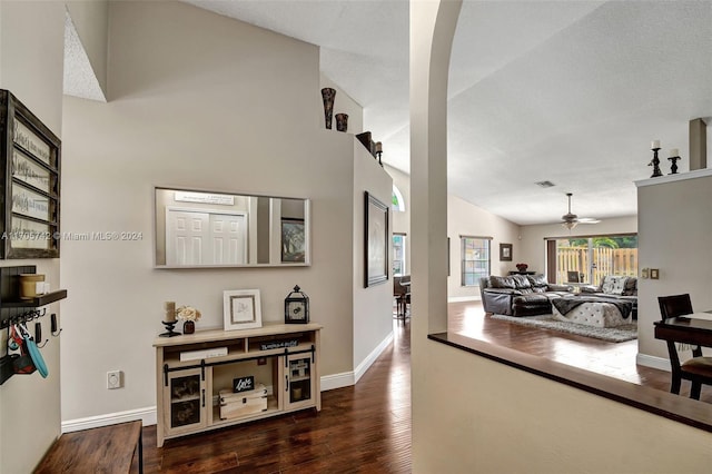 corridor with a textured ceiling, high vaulted ceiling, and dark hardwood / wood-style floors