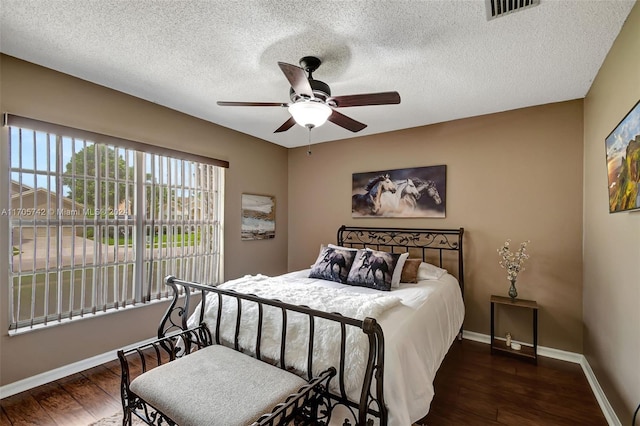 bedroom with a textured ceiling, ceiling fan, and dark wood-type flooring