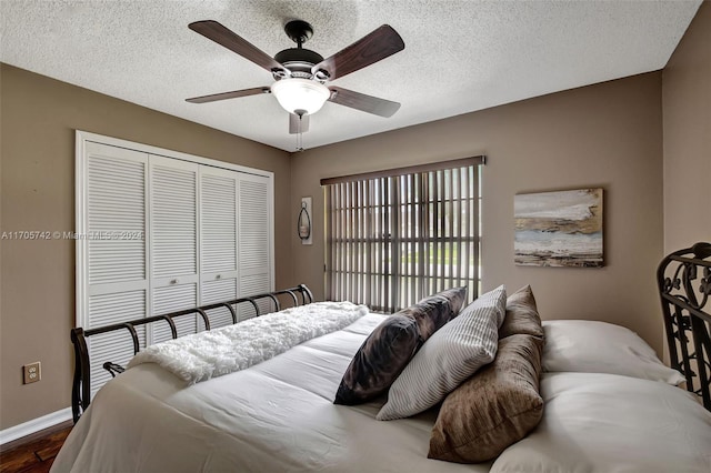 bedroom featuring a textured ceiling, ceiling fan, dark wood-type flooring, and a closet