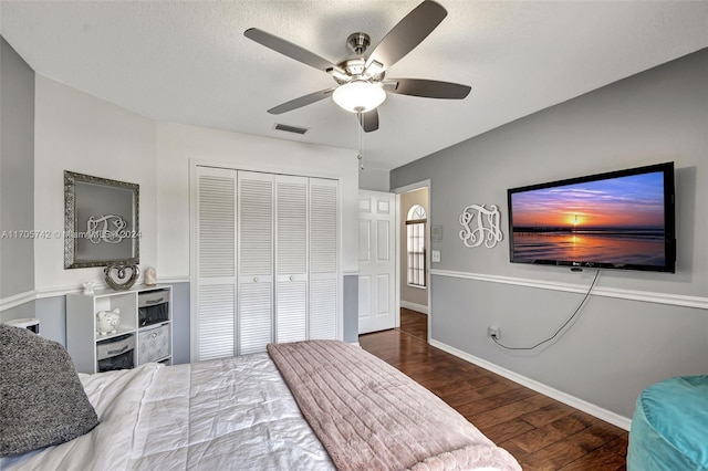 bedroom featuring a textured ceiling, ceiling fan, a closet, and dark hardwood / wood-style floors