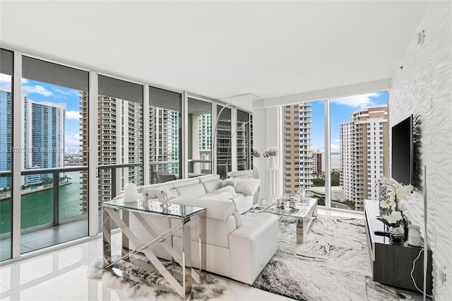 living room featuring a water view, tile patterned floors, floor to ceiling windows, and a healthy amount of sunlight