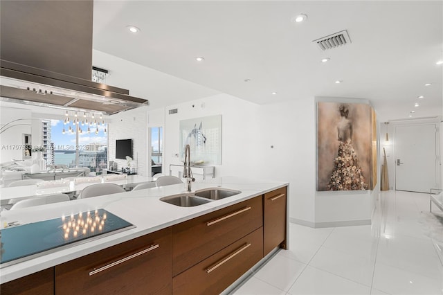 kitchen with light stone countertops, light tile patterned floors, island range hood, and sink