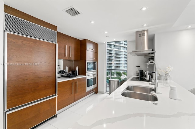 kitchen with paneled refrigerator, a wall of windows, light stone counters, range hood, and light tile patterned floors