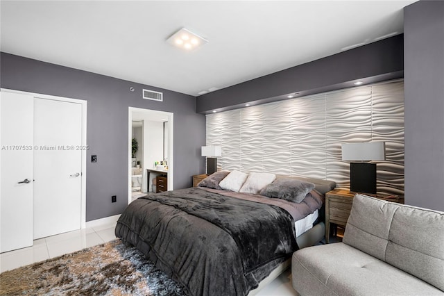 bedroom with connected bathroom and light tile patterned flooring