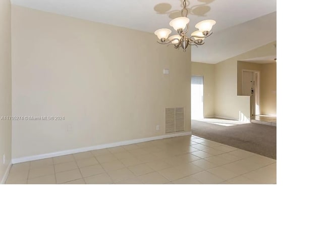 carpeted spare room with an inviting chandelier