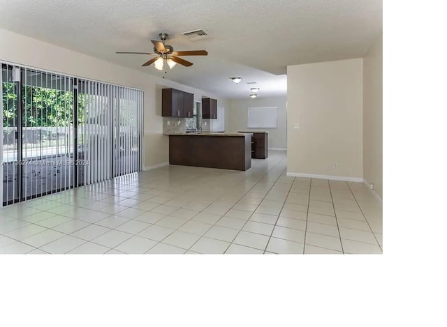 kitchen with ceiling fan, light tile patterned flooring, kitchen peninsula, and a textured ceiling