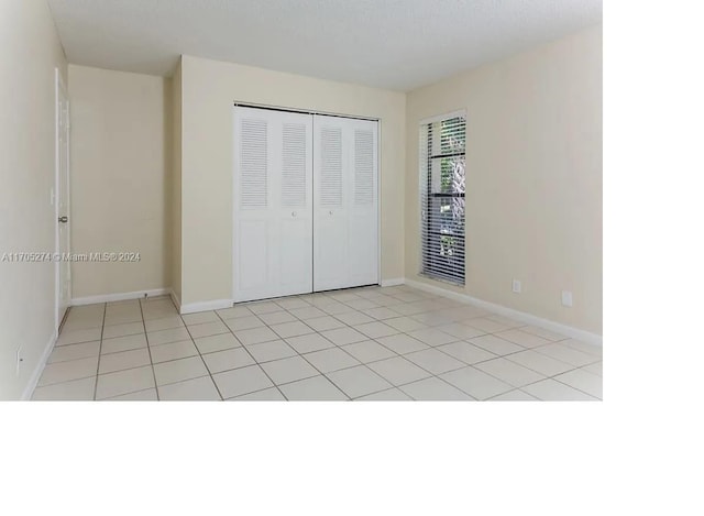 unfurnished bedroom featuring light tile patterned flooring and a closet