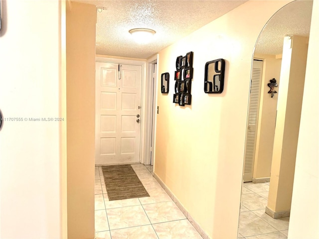 corridor with light tile patterned floors and a textured ceiling