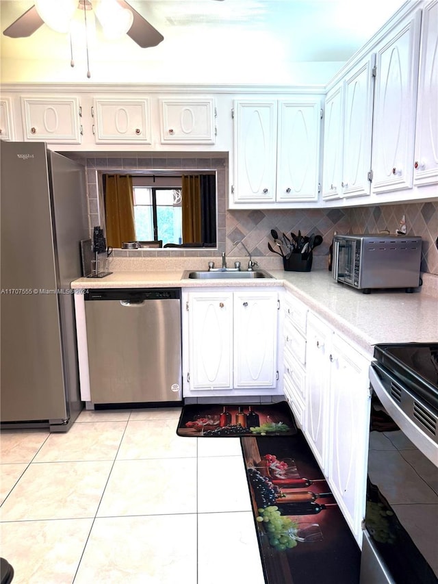 kitchen featuring tasteful backsplash, stainless steel appliances, sink, light tile patterned floors, and white cabinets