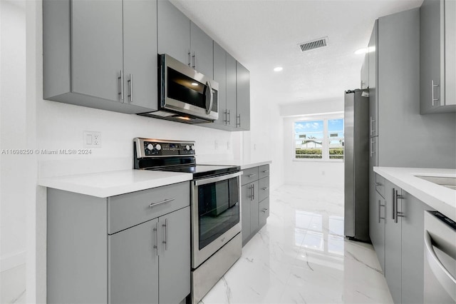 kitchen featuring a textured ceiling, stainless steel appliances, and gray cabinetry