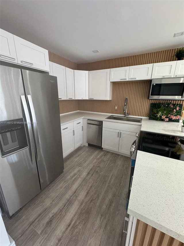 kitchen featuring dark wood-type flooring, appliances with stainless steel finishes, sink, and white cabinets