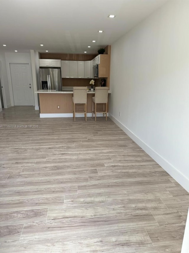 kitchen with white cabinetry, a kitchen island, a breakfast bar, and appliances with stainless steel finishes