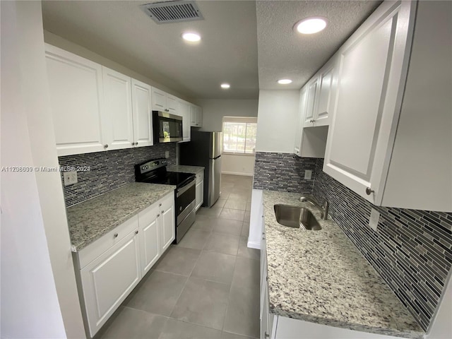 kitchen featuring light stone counters, stainless steel appliances, sink, white cabinetry, and light tile patterned flooring