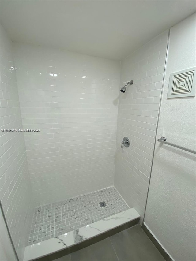 bathroom featuring tile patterned flooring and tiled shower