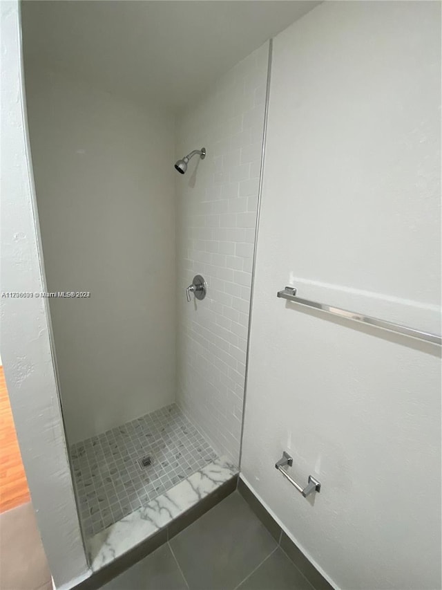 bathroom with tiled shower and tile patterned flooring