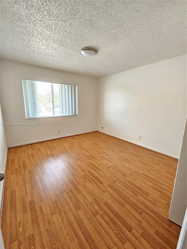 empty room with hardwood / wood-style floors and a textured ceiling