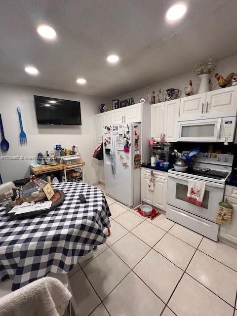 kitchen with white cabinetry, light tile patterned floors, and white appliances