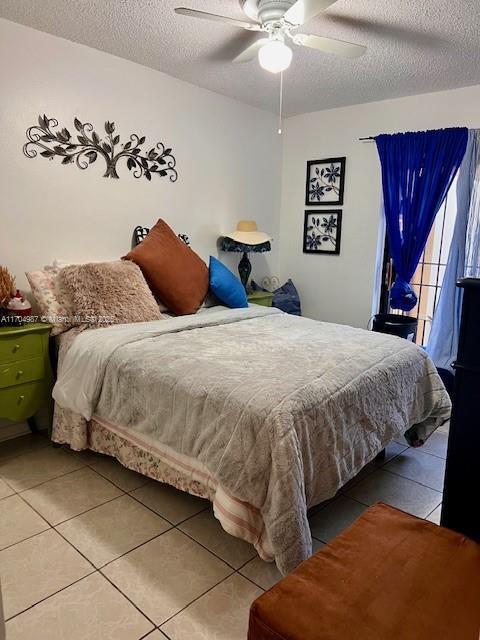 tiled bedroom featuring a textured ceiling and ceiling fan