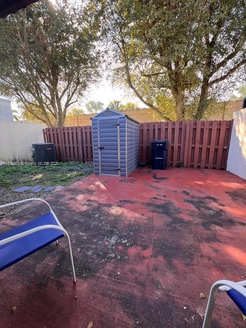 view of yard featuring a patio, central air condition unit, and a storage unit