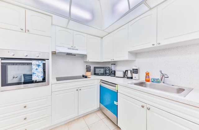 kitchen with sink, white cabinets, black appliances, and light tile patterned floors