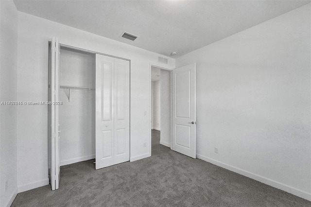 unfurnished bedroom with dark colored carpet and a closet