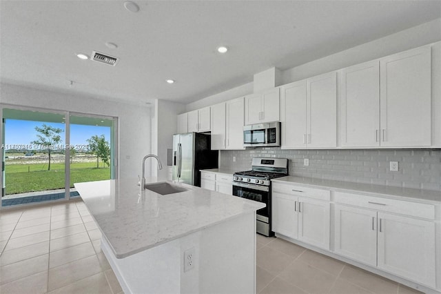 kitchen with white cabinets, stainless steel appliances, a kitchen island with sink, and sink