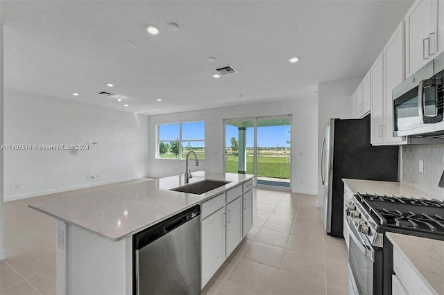 kitchen featuring light stone countertops, appliances with stainless steel finishes, a kitchen island with sink, sink, and white cabinets