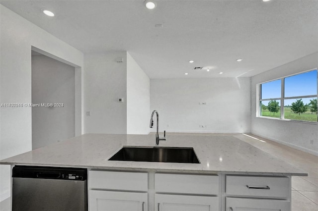 kitchen with sink, stainless steel dishwasher, light stone countertops, light tile patterned floors, and white cabinetry