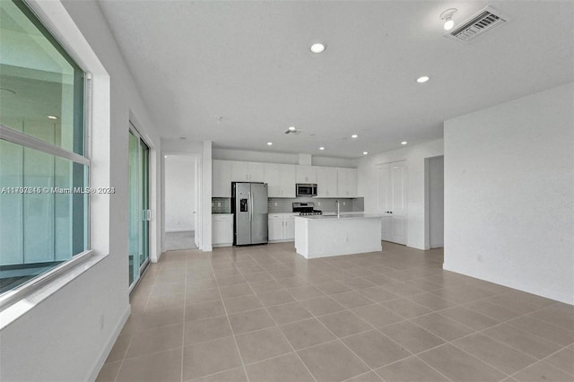 kitchen with white cabinets, sink, an island with sink, appliances with stainless steel finishes, and light tile patterned flooring