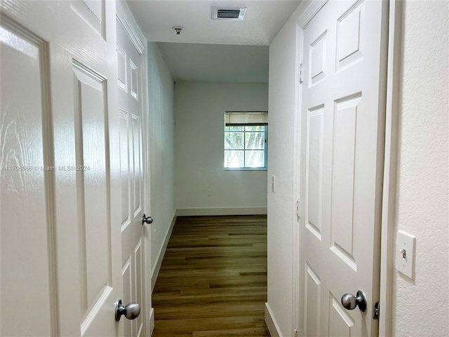 hallway with dark wood-type flooring and a textured ceiling