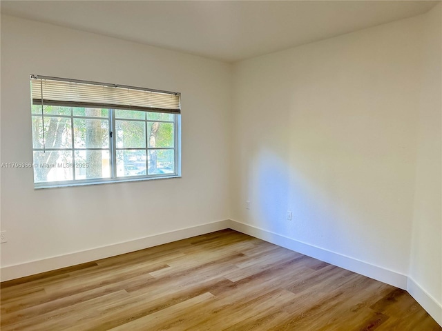 spare room featuring baseboards and light wood-style floors