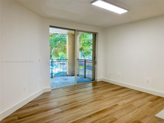 empty room with baseboards and light wood-type flooring