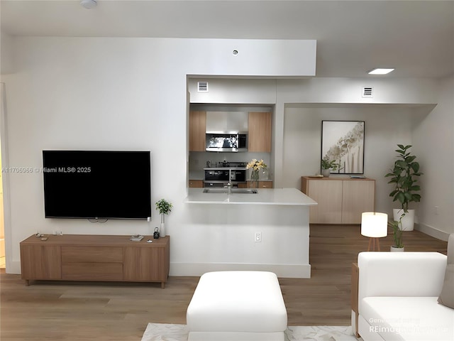 living area featuring visible vents, light wood-style flooring, and baseboards