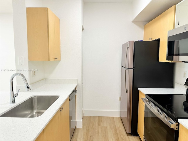 kitchen with baseboards, light brown cabinets, a sink, stainless steel appliances, and light wood-style flooring