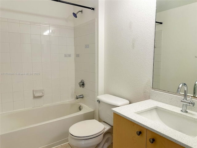 bathroom with a textured wall, toilet, vanity, and shower / washtub combination