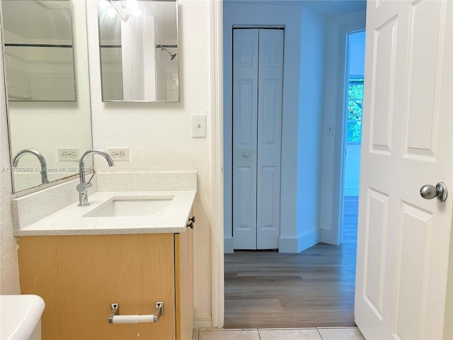 bathroom featuring vanity, a closet, baseboards, and wood finished floors