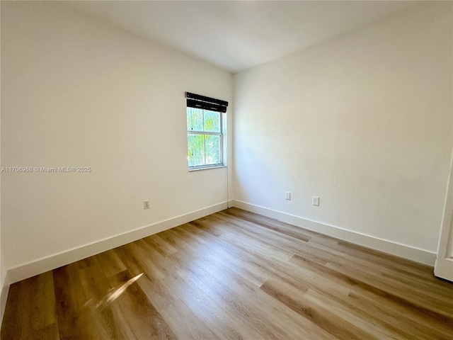 spare room with baseboards and wood finished floors