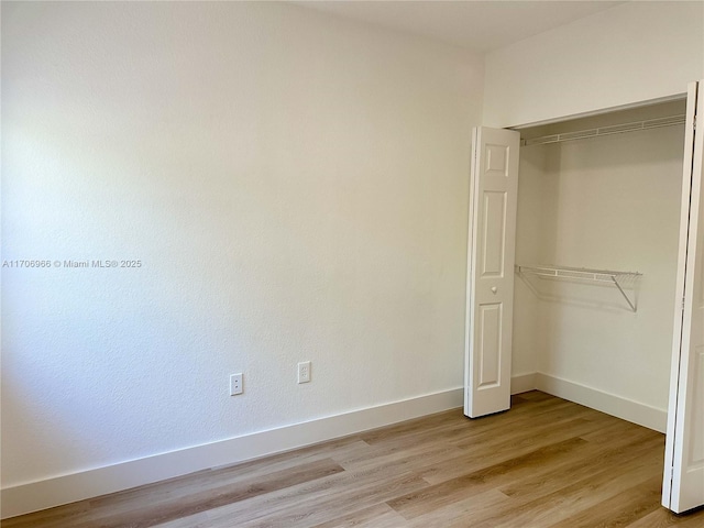 unfurnished bedroom with light wood-style floors, a closet, and baseboards