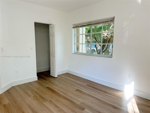 unfurnished bedroom featuring a closet, light wood-style floors, and baseboards