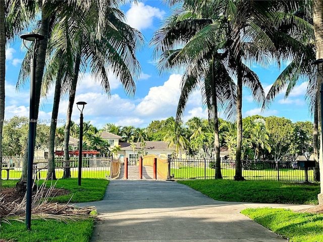 view of property's community featuring a lawn, fence, and a gate